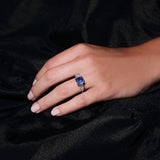 Maria Jose Jewelry Cushion Sapphire Three Stone Diamond Ring on model's left hand against a black velvet blanket