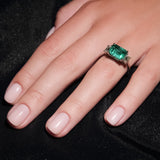 Maria Jose Jewelry East West Colombian Emerald Ring on model's left hand against a black velvet blanket